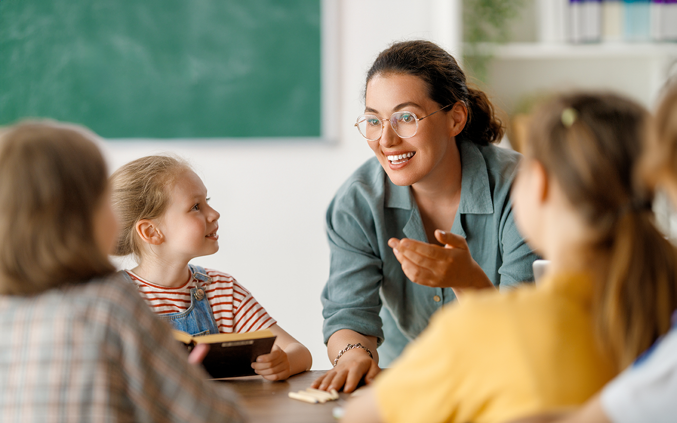 Lehrerin im Gespräch mit Grundschulkindern im Unterricht