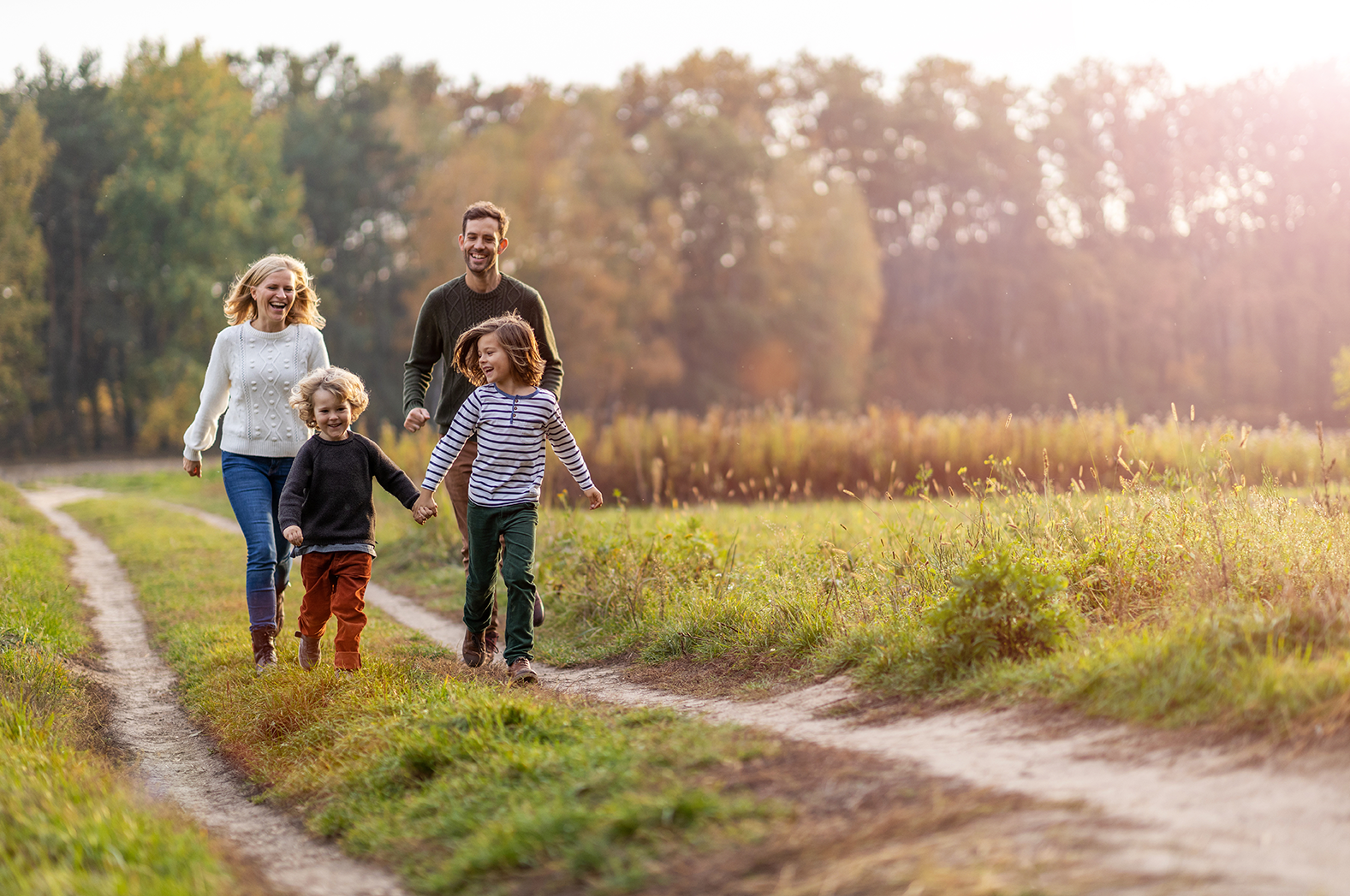 Glückliche Familie beim Spaziergang auf einem Feldweg im Herbst