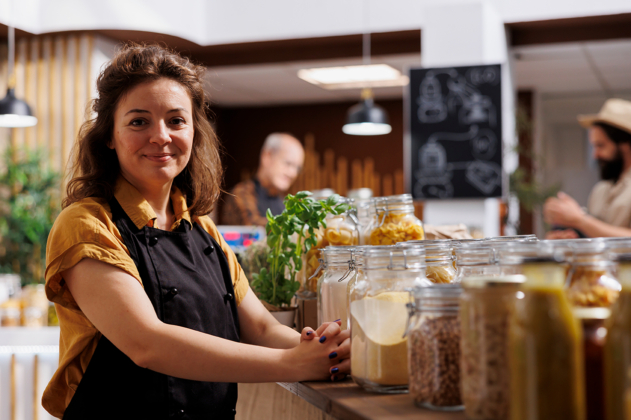 Selbstständige Ladenbetreiberin lächelt in einem Naturkostladen in die Kamera