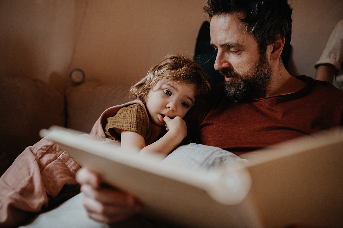 Vater liest seinem kleinen Kind ein Buch vor auf dem Sofa