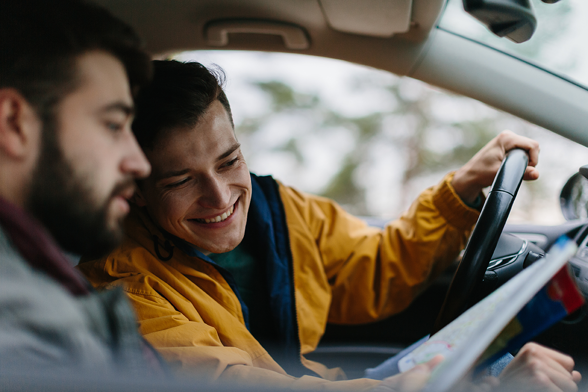 Paar im Auto schaut lächelnd auf eine Straßenkarte