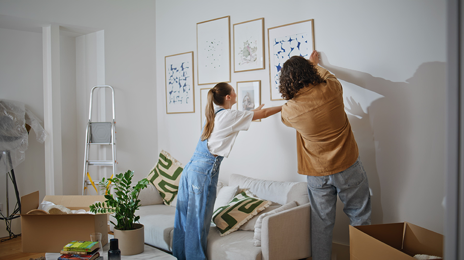 Paar hängt gemeinsam Bilder in der neuen Wohnung auf