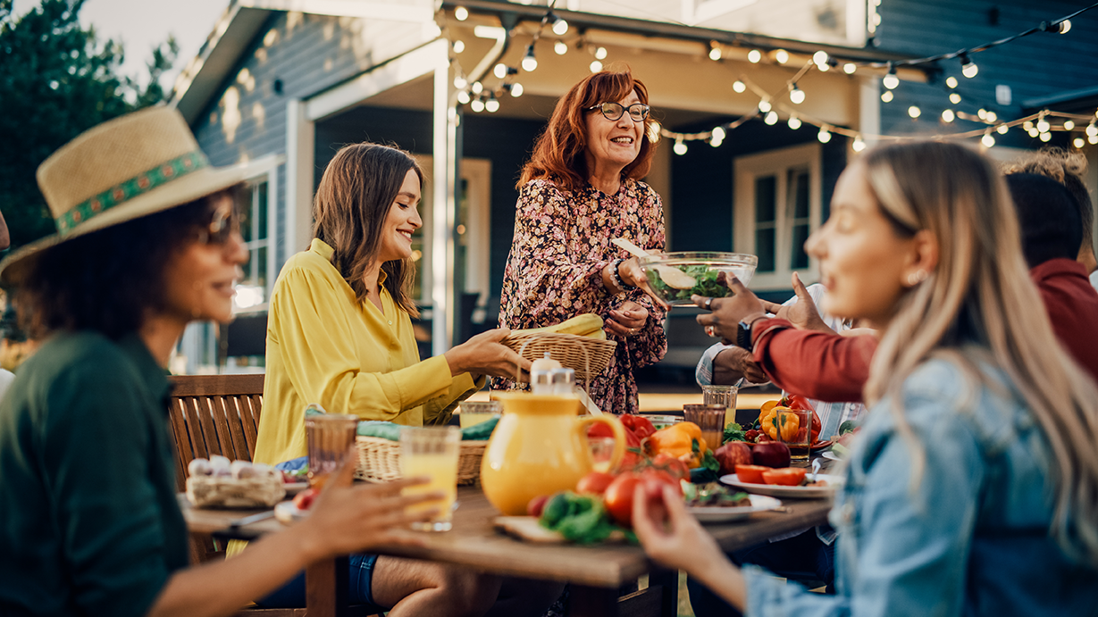 Gruppe von Menschen beim geselligen Abendessen im Garten eines Hauses
