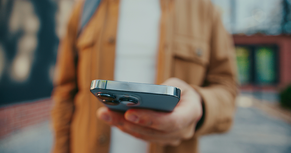 Person hält ein Smartphone in der Hand auf der Straße